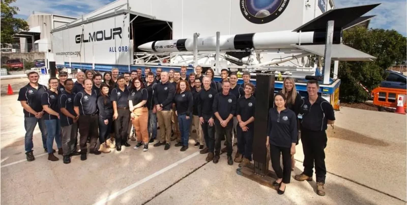 The Gilmour Space team standing in front of a sub-orbital rocket on its launch trailer